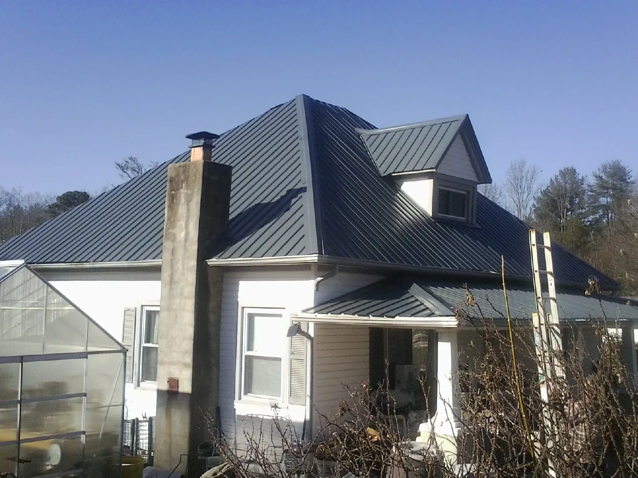 Dark blue standing seam metal roof on a white farmhouse with dormer — Slate & Tile Roof Repair by Roofing Brothers in Merced