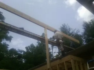 Carpenter setting a ridge beam over a new addition frame — Ice Dam Removal by Roofing Brothers in Merced