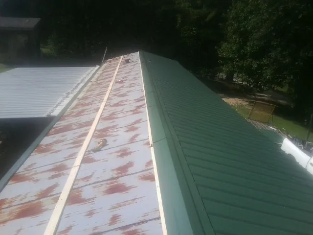 Old rusted panels beside newly installed green metal roofing — Wind Damage Roof Repair by Roofing Brothers in Merced