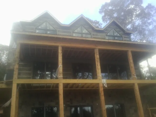 Dormers and porch framing on a large log home under construction — Roof Coating work by our crew in Merced