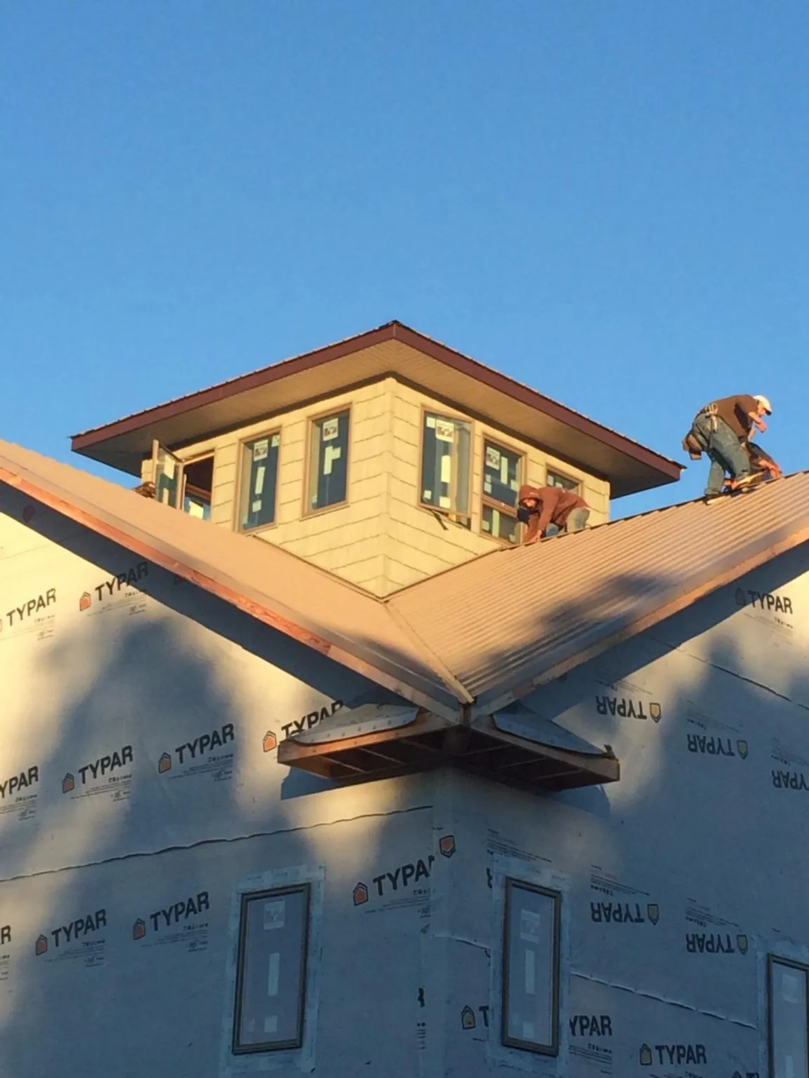 Roofers working around a rooftop cupola on a new metal roof at sunset — Roof Waterproofing in Merced by Roofing Brothers